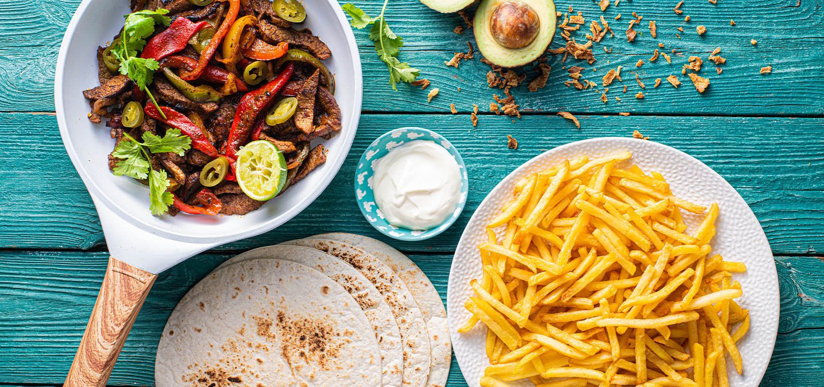 Fajitas de vită cu ceapă, ardei și smântână și cartofi prăjiți subțiri